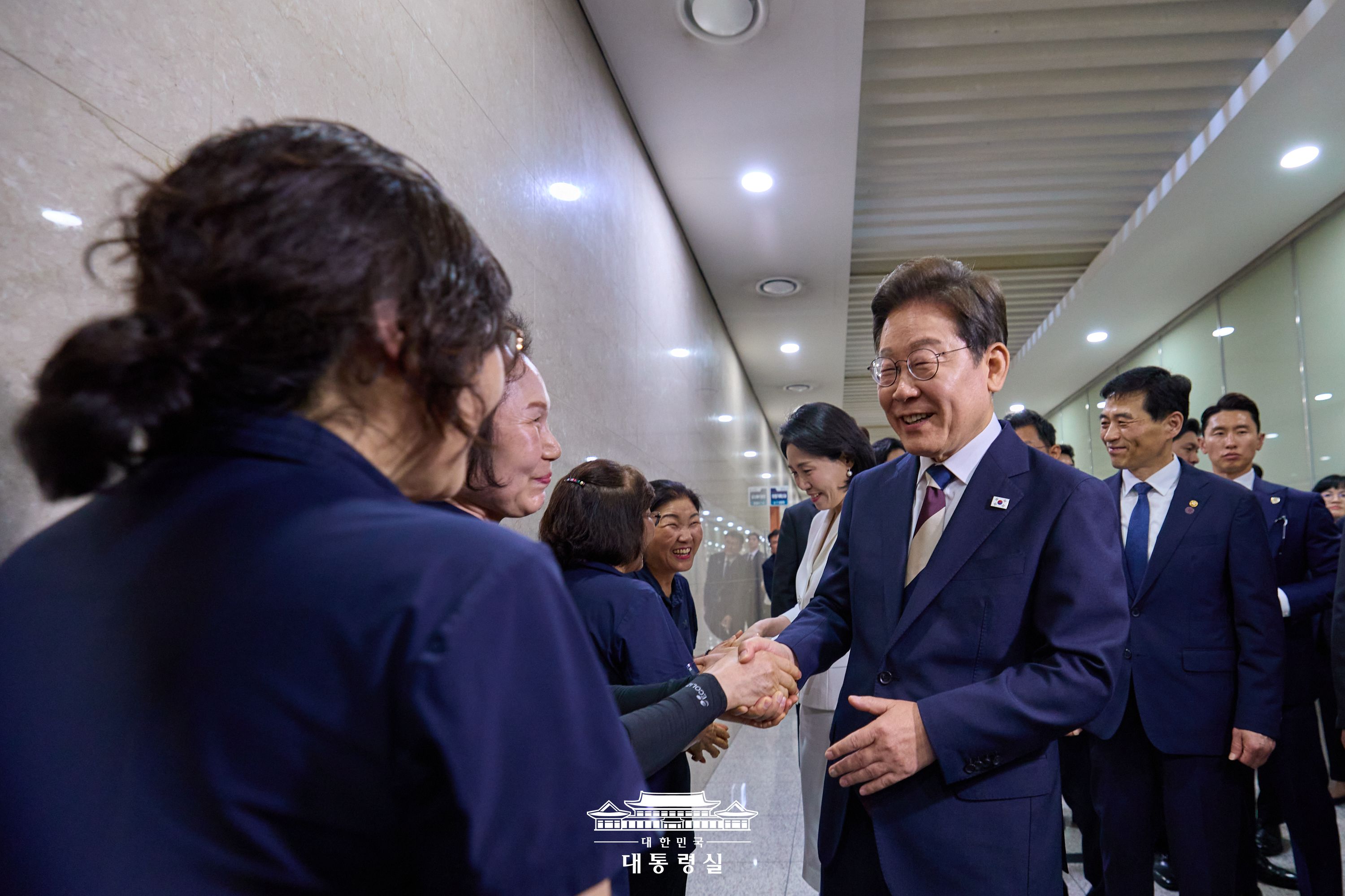 이재명 대통령이 국회 내 근로자들과 악수를 하고 있다.